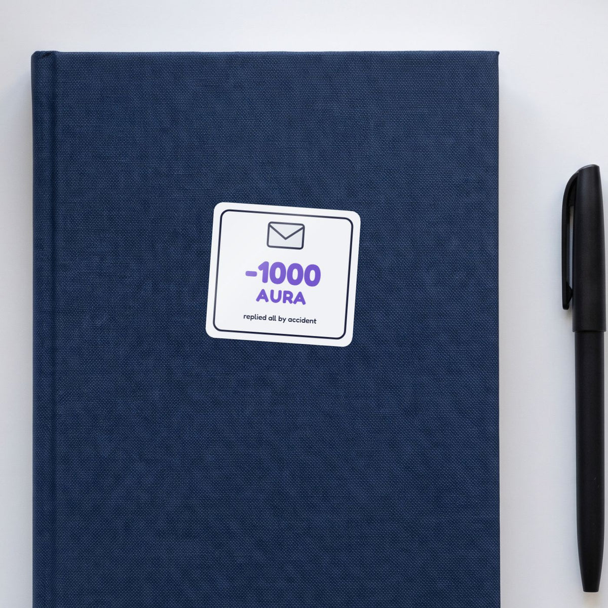 -1000 Aura: Replied All sticker on a navy notebook