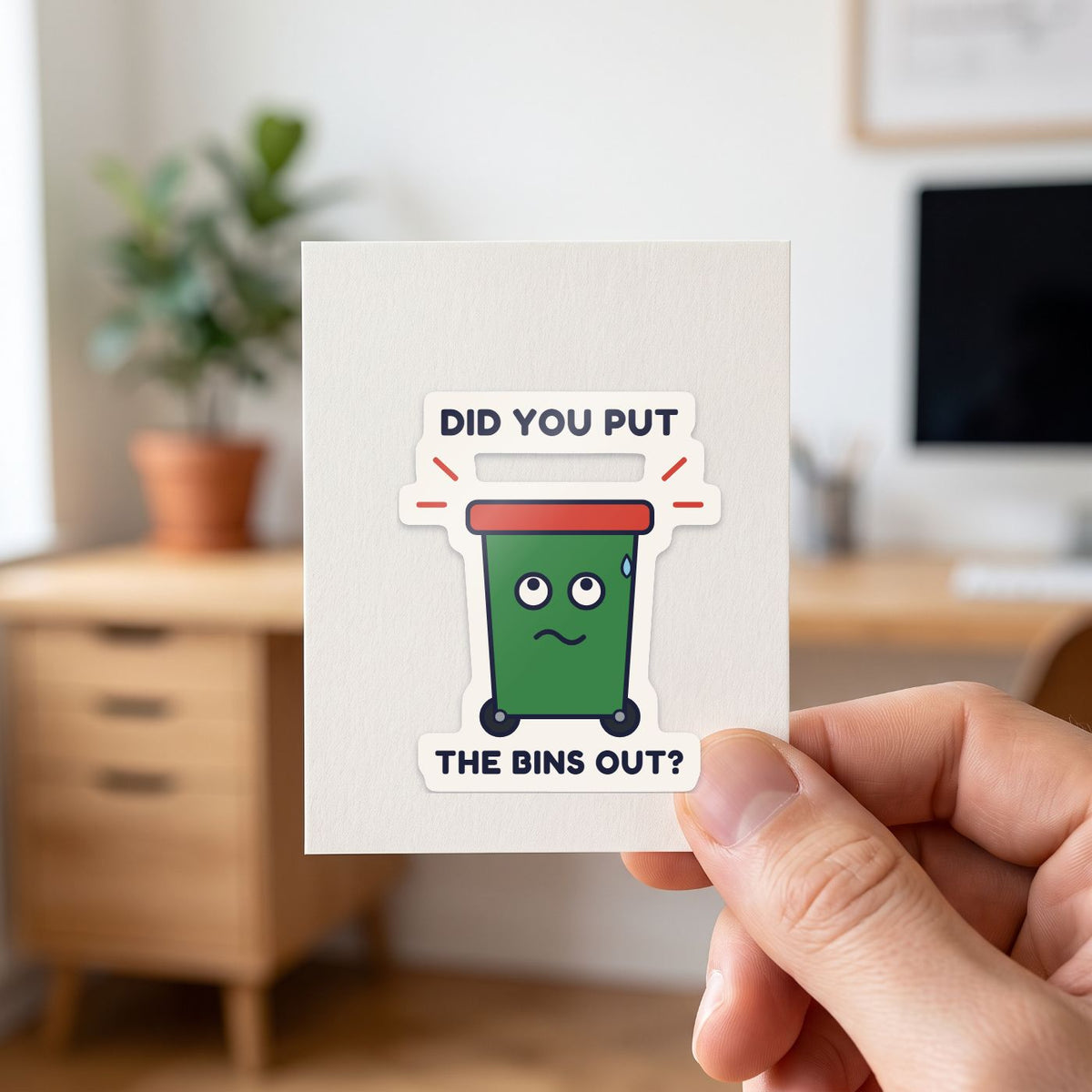 Did You Put the Bins Out? sticker held in a hand on its white backing card