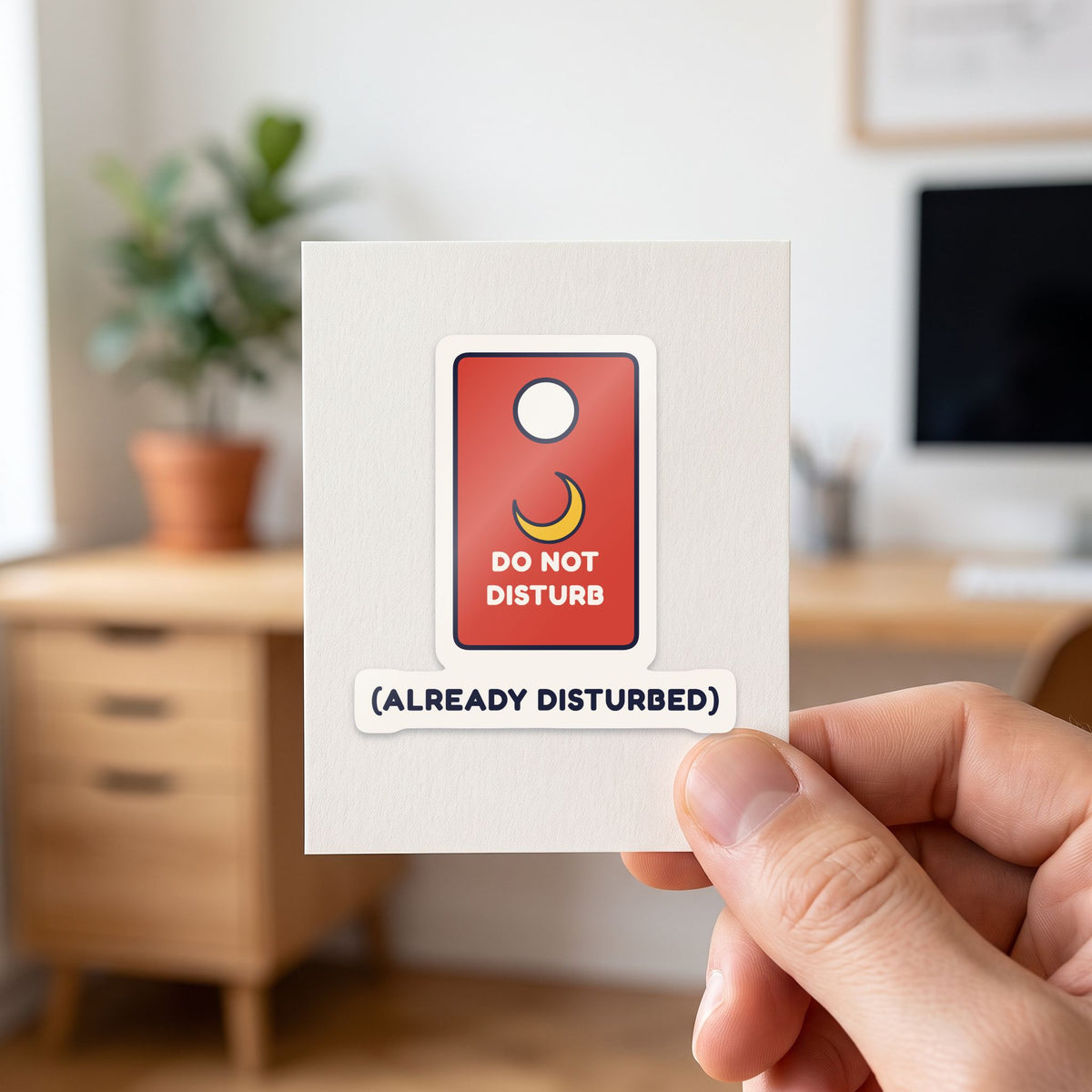Do Not Disturb (Already Disturbed) sticker held in a hand on its white backing card
