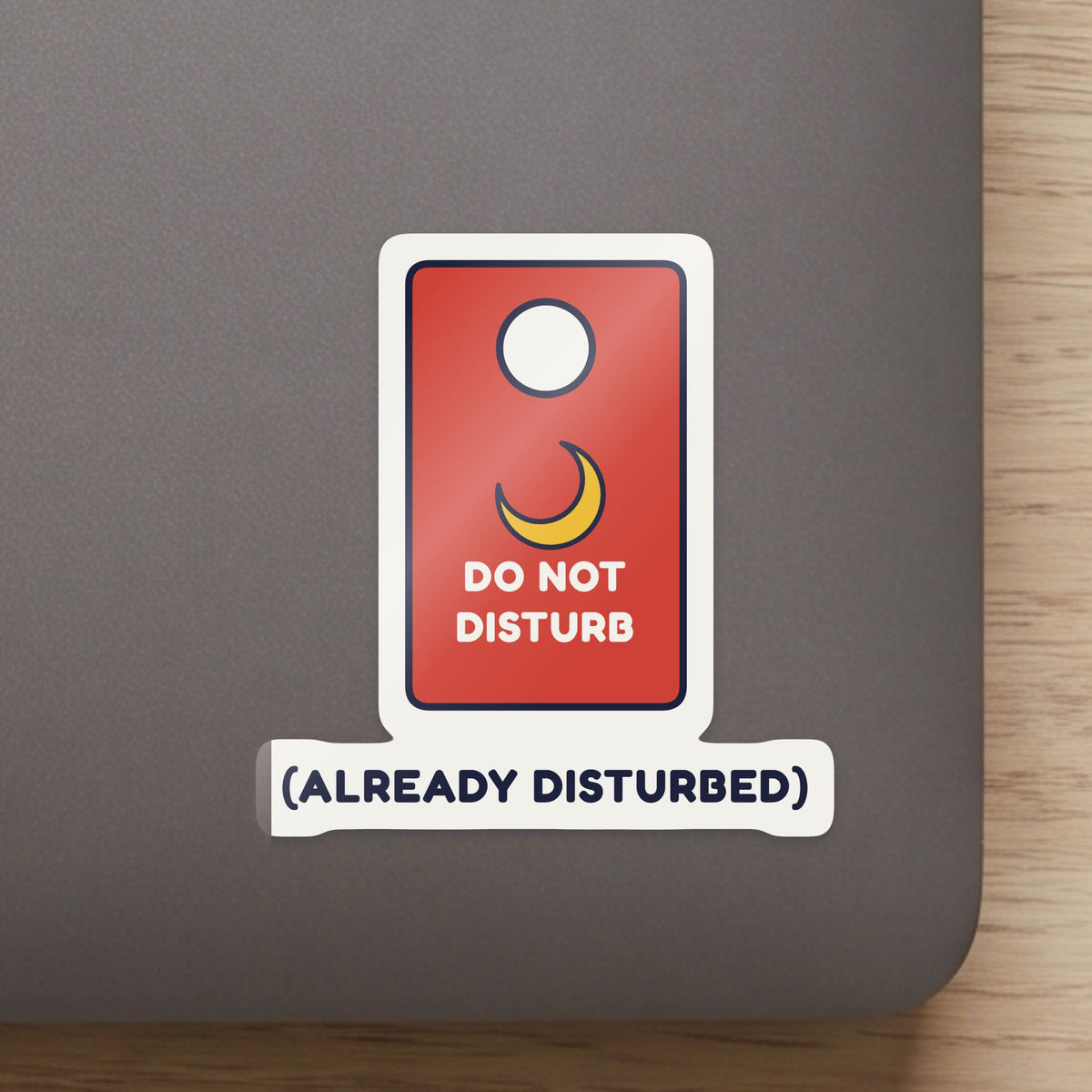 Do Not Disturb (Already Disturbed) sticker close up on a laptop lid, showing the gloss and the white cut edge