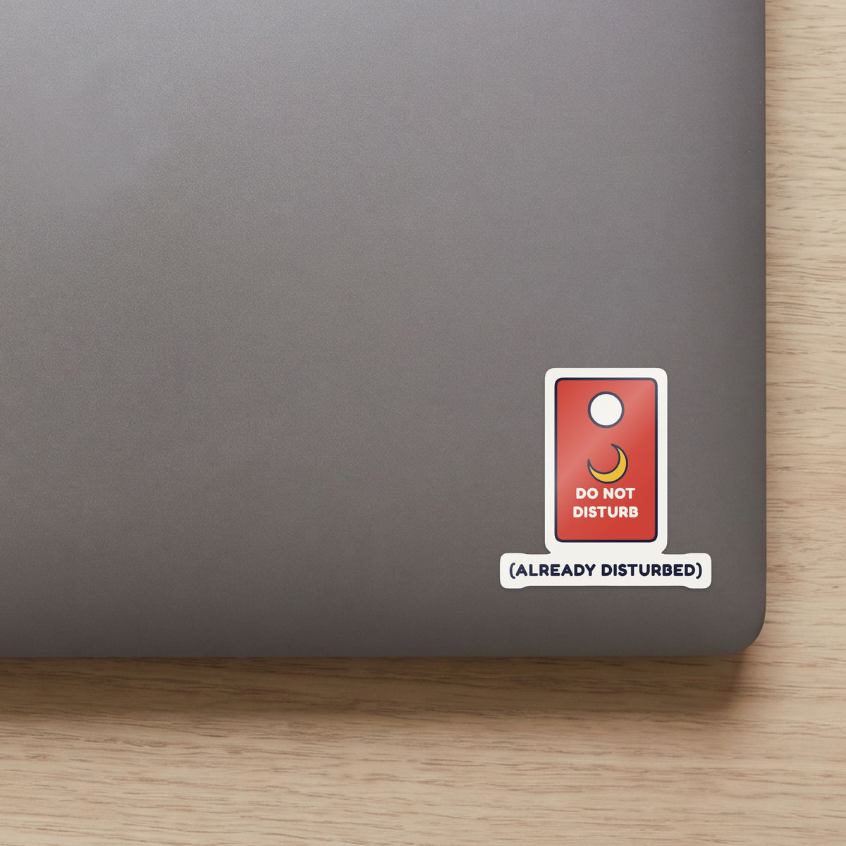 Do Not Disturb (Already Disturbed) sticker on the lid of a grey laptop