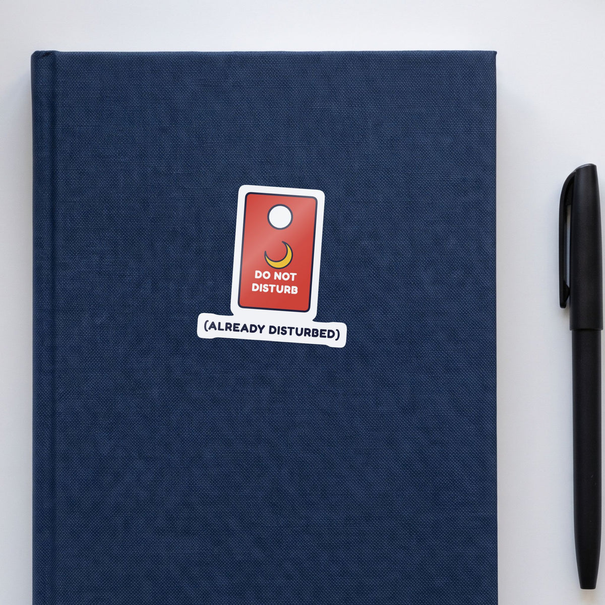 Do Not Disturb (Already Disturbed) sticker on a navy notebook