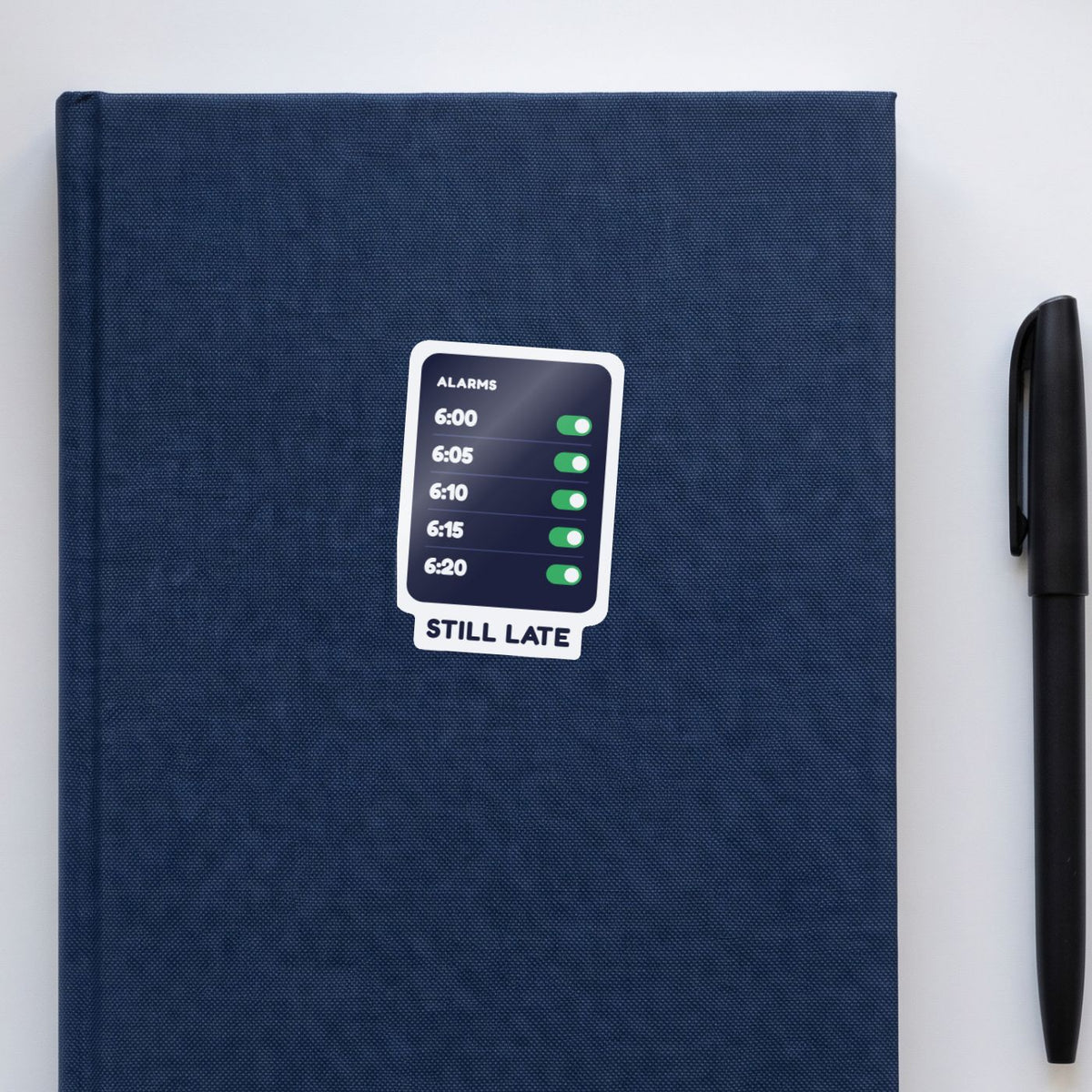 Five Alarms, Still Late sticker on a navy notebook