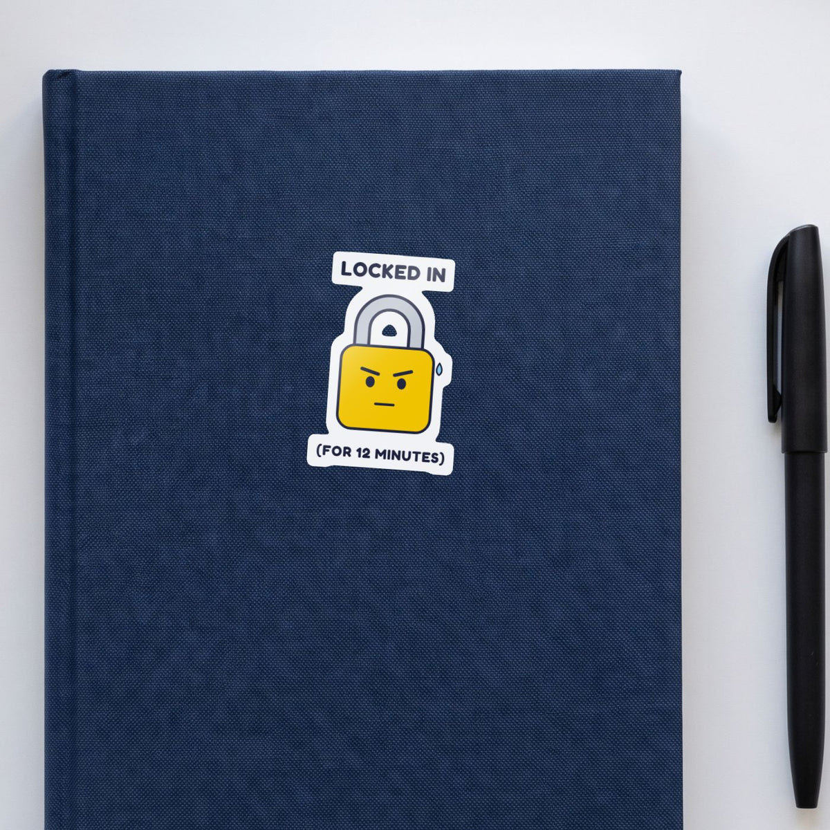Locked In (for 12 Minutes) sticker on a navy notebook