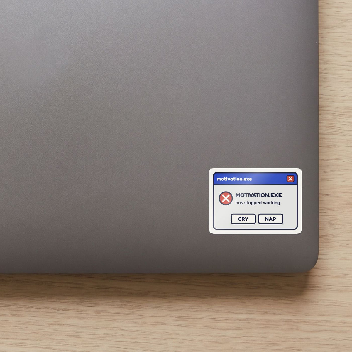 Motivation.exe Has Stopped Working sticker on the lid of a grey laptop