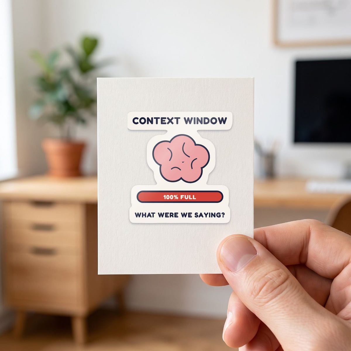 My Context Window Is Full sticker held in a hand on its white backing card