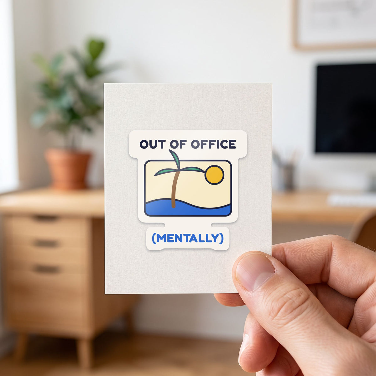 Out of Office (Mentally) sticker held in a hand on its white backing card