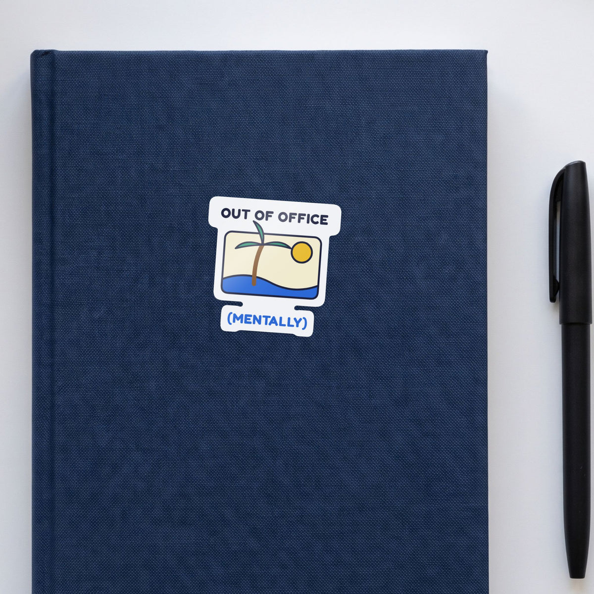 Out of Office (Mentally) sticker on a navy notebook