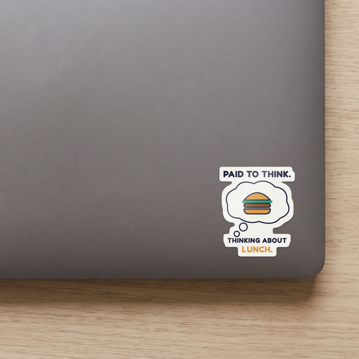 Paid to Think. Thinking About Lunch. sticker on the lid of a grey laptop