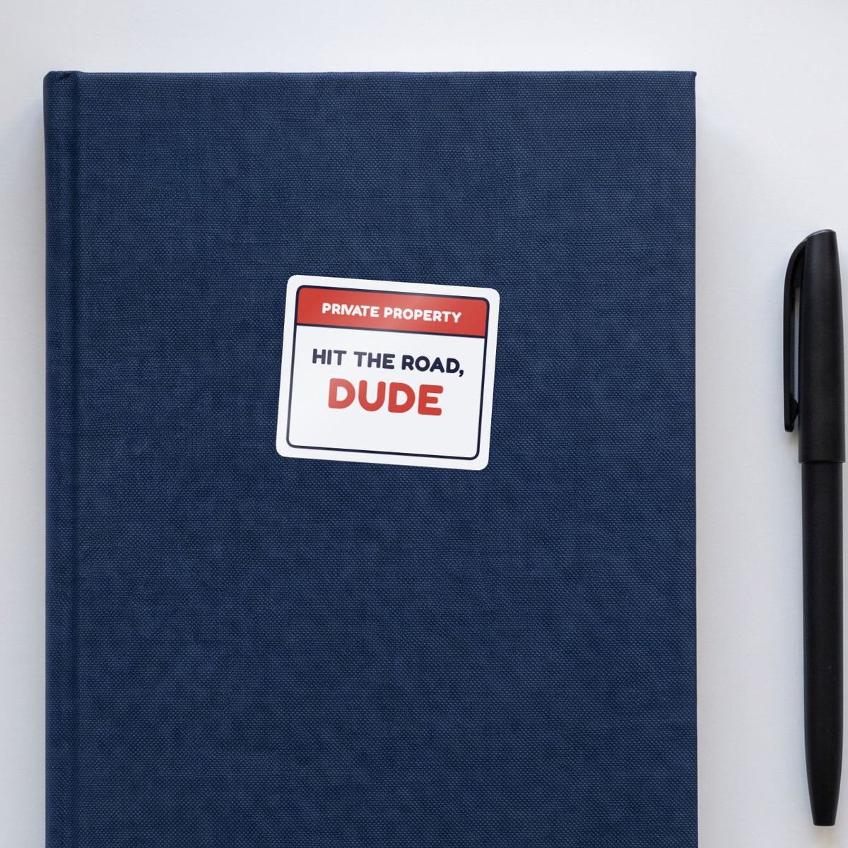 Private Property: Hit the Road, Dude sticker on a navy notebook