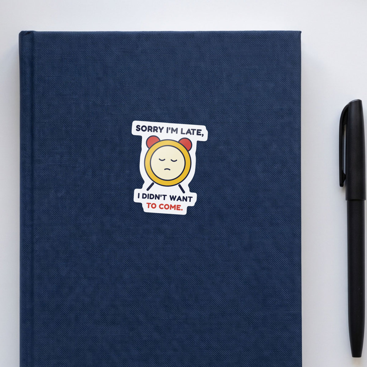 Sorry I'm Late, I Didn't Want to Come sticker on a navy notebook
