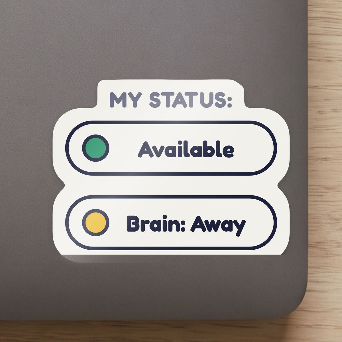 Status: Available. Brain: Away. sticker close up on a laptop lid, showing the gloss and the white cut edge