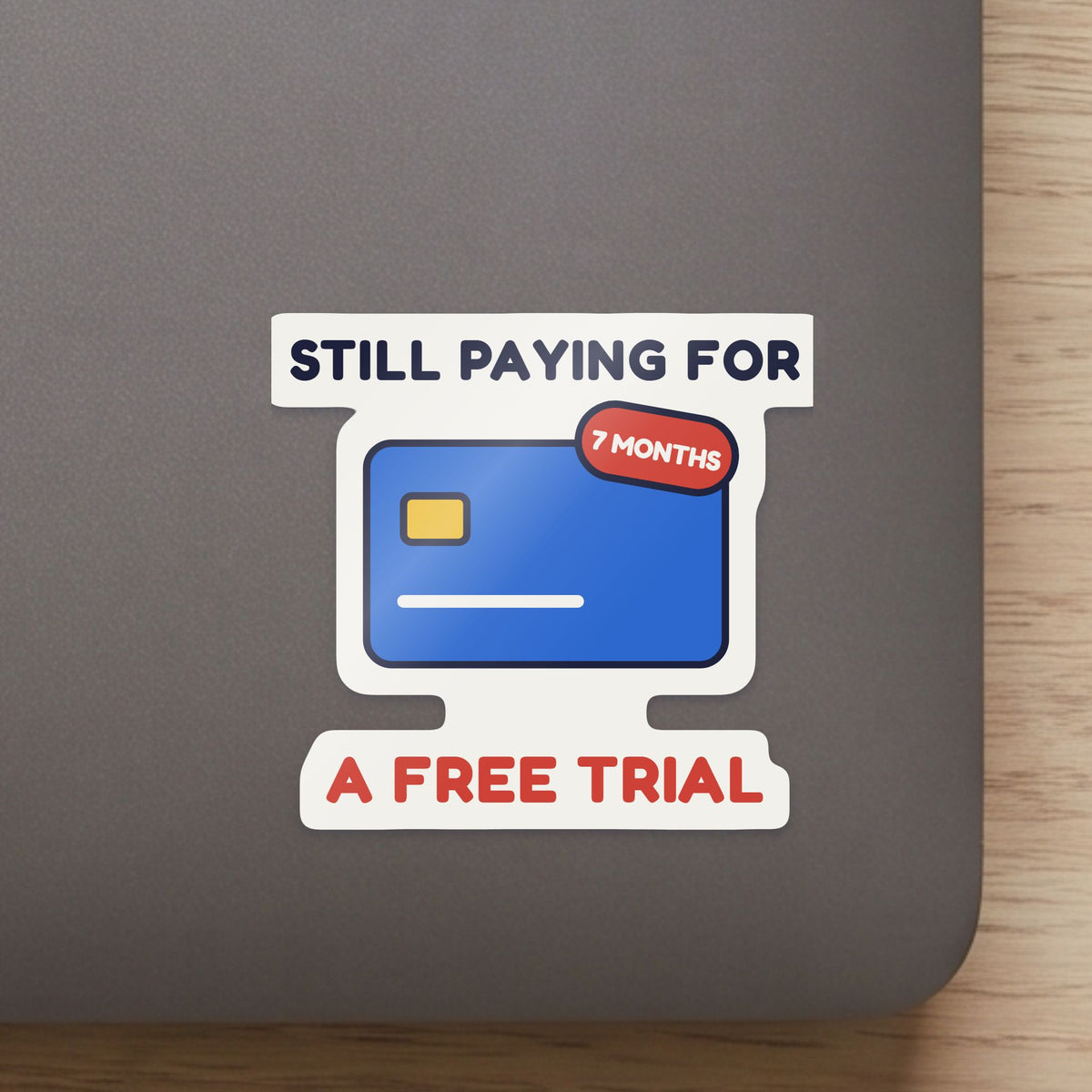 Still Paying for a Free Trial sticker close up on a laptop lid, showing the gloss and the white cut edge