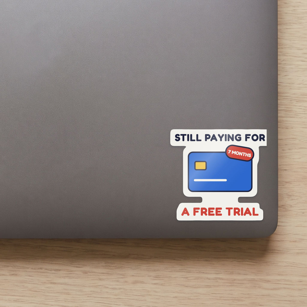 Still Paying for a Free Trial sticker on the lid of a grey laptop