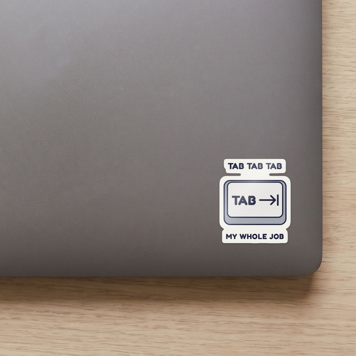 Tab Tab Tab sticker on the lid of a grey laptop
