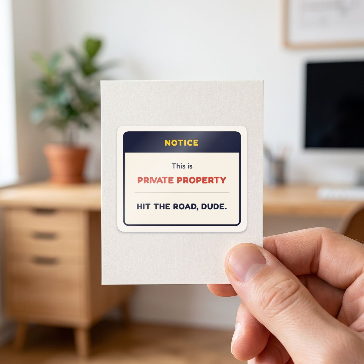 This Is Private Property sticker held in a hand on its white backing card