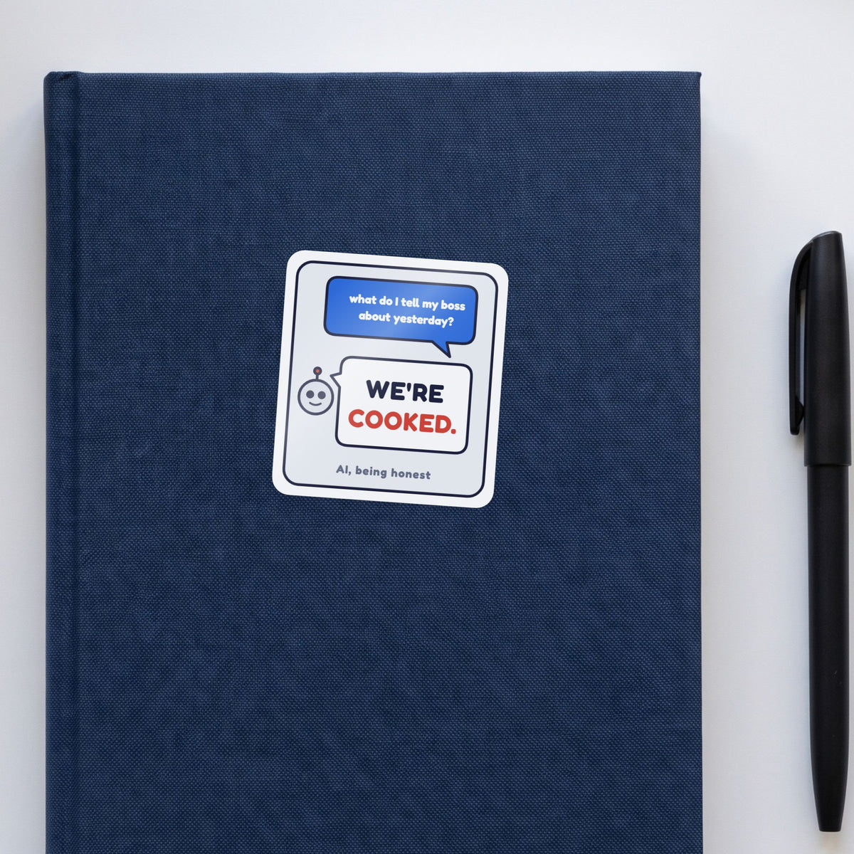 We're Cooked sticker on a navy notebook