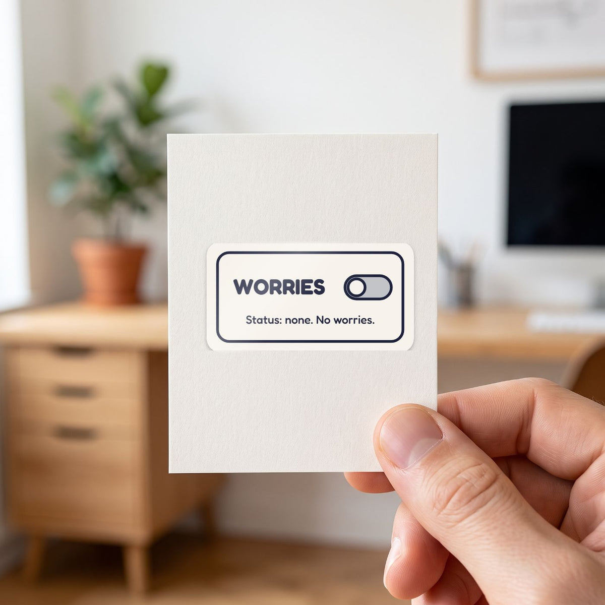 Worries: Off sticker held in a hand on its white backing card