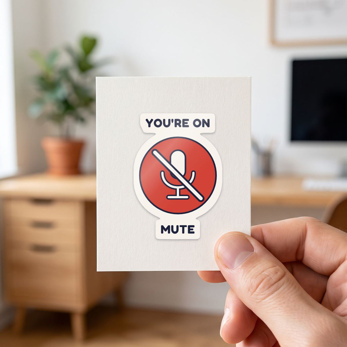 You're on Mute sticker held in a hand on its white backing card