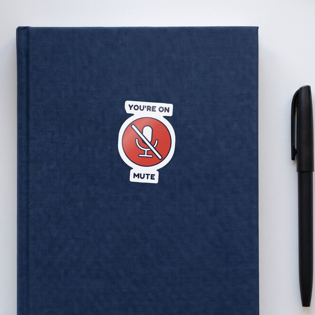 You're on Mute sticker on a navy notebook